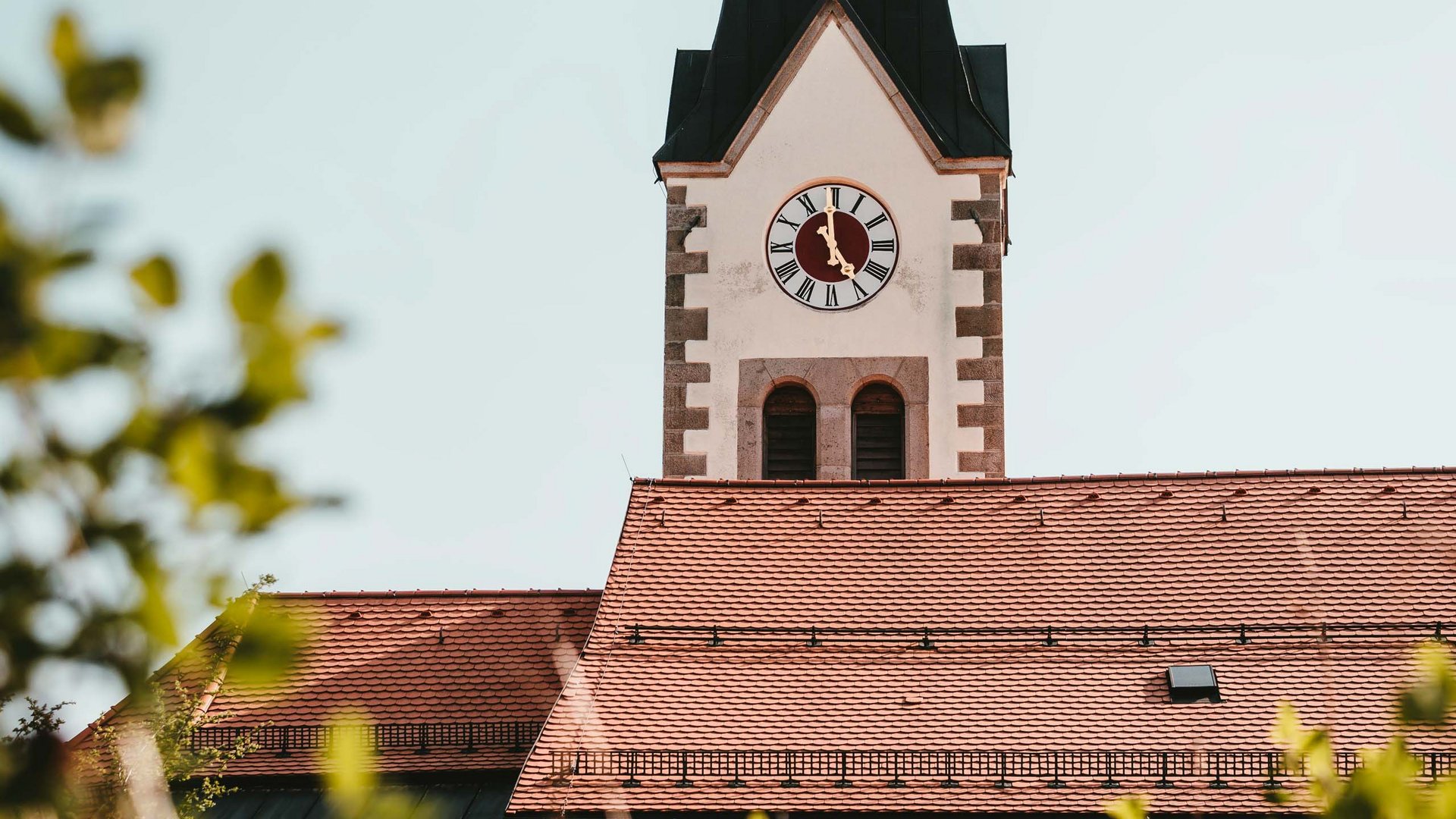 Sehenswürdigkeiten rund um Rattenberg Kirchturm mit Uhr und rotem Ziegeldach im Sonnenschein
