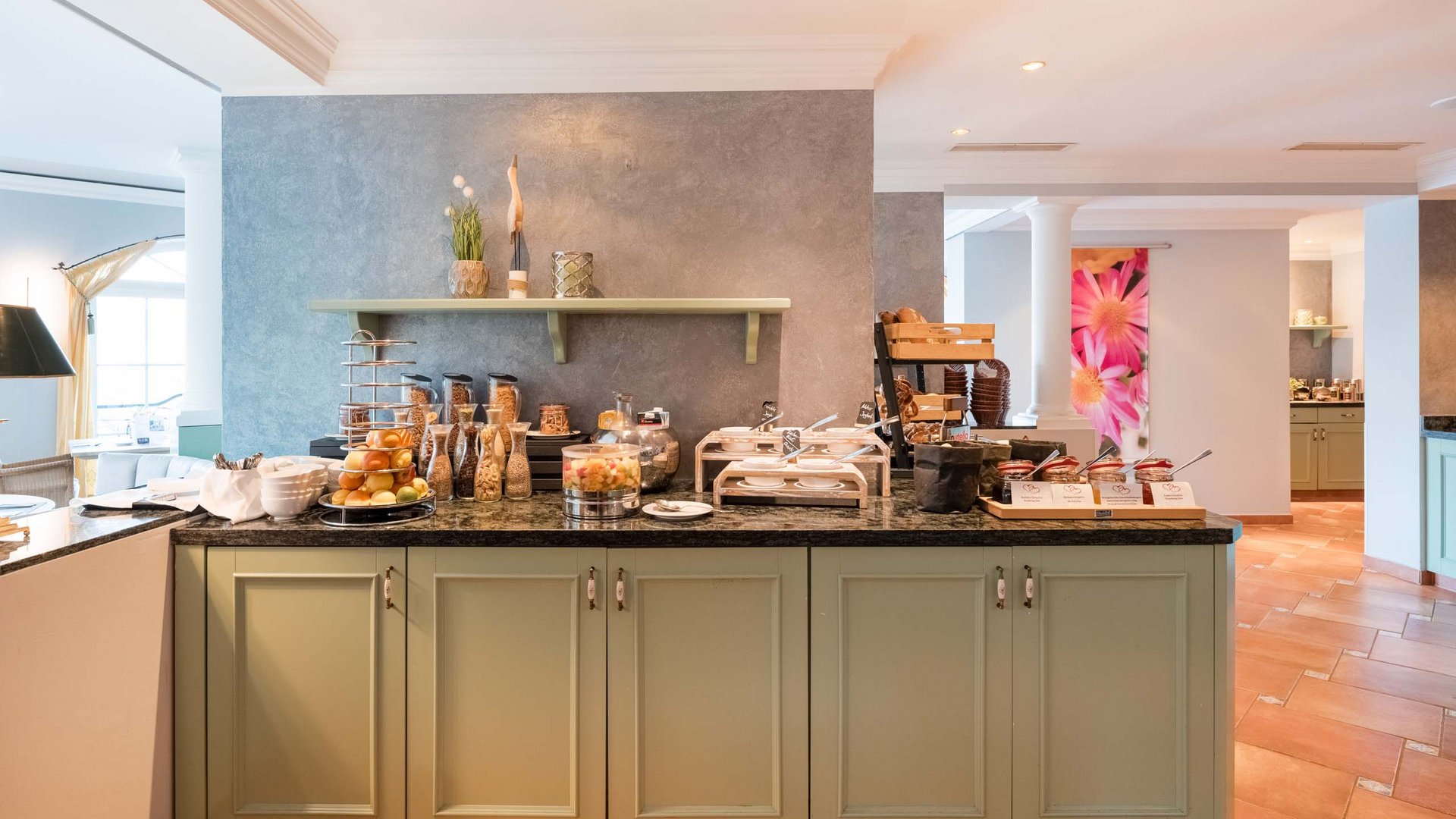 Buffet mit verschiedenen Frühstückszutaten und Obst in einem hellen Raum