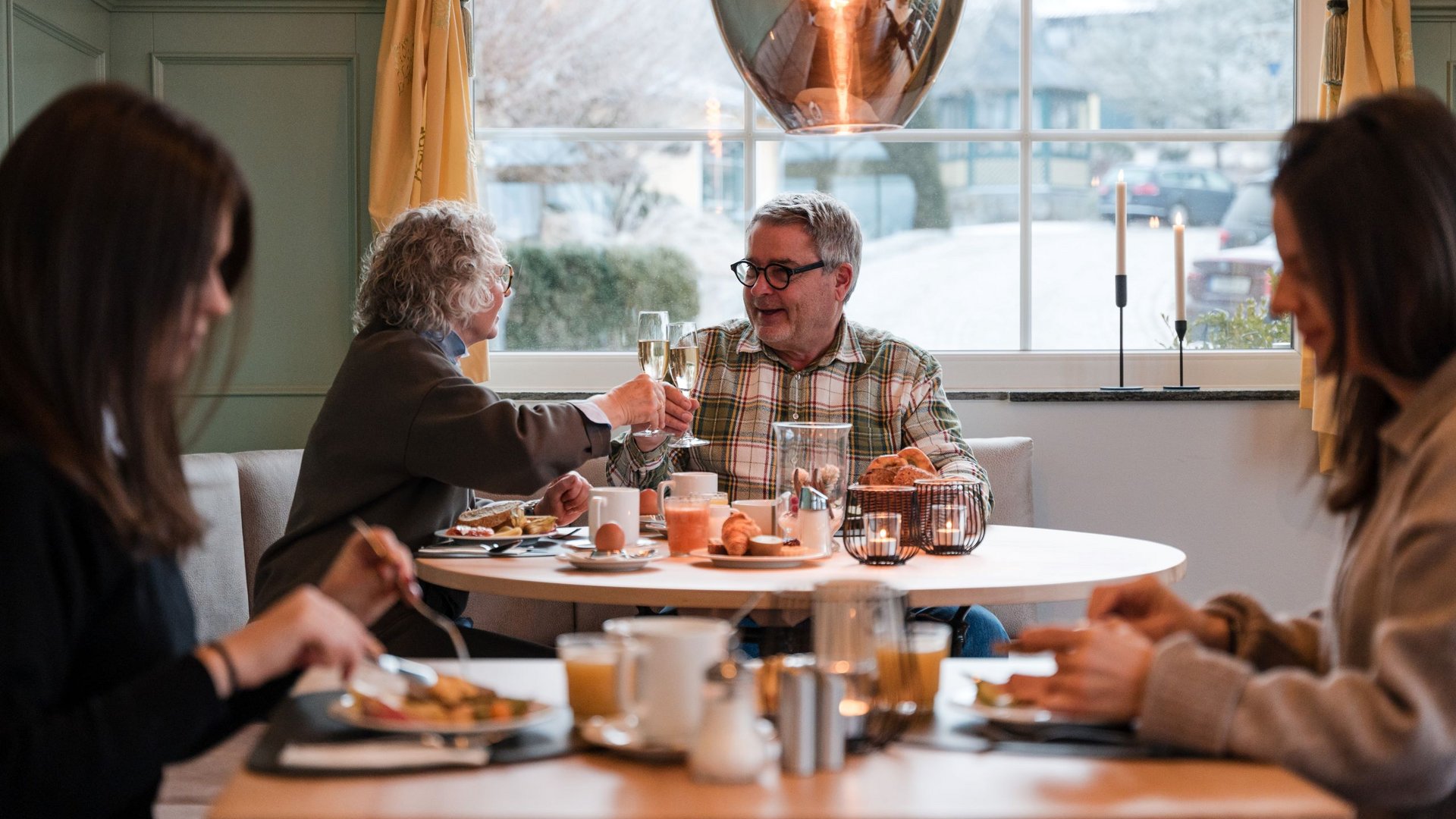 Older couple clinking champagne glasses during a cozy breakfast