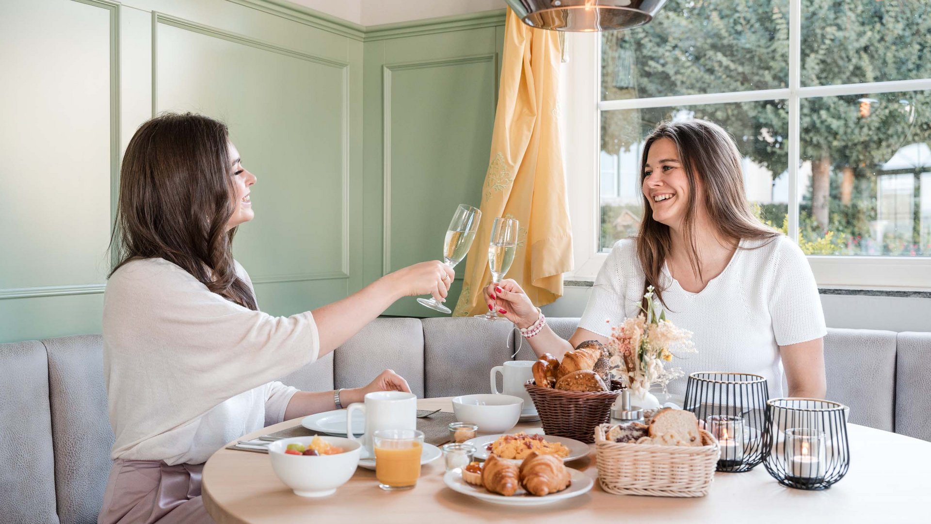 Frühstück in Rattenberg Zwei Frauen stoßen beim Frühstück mit Sektgläsern an