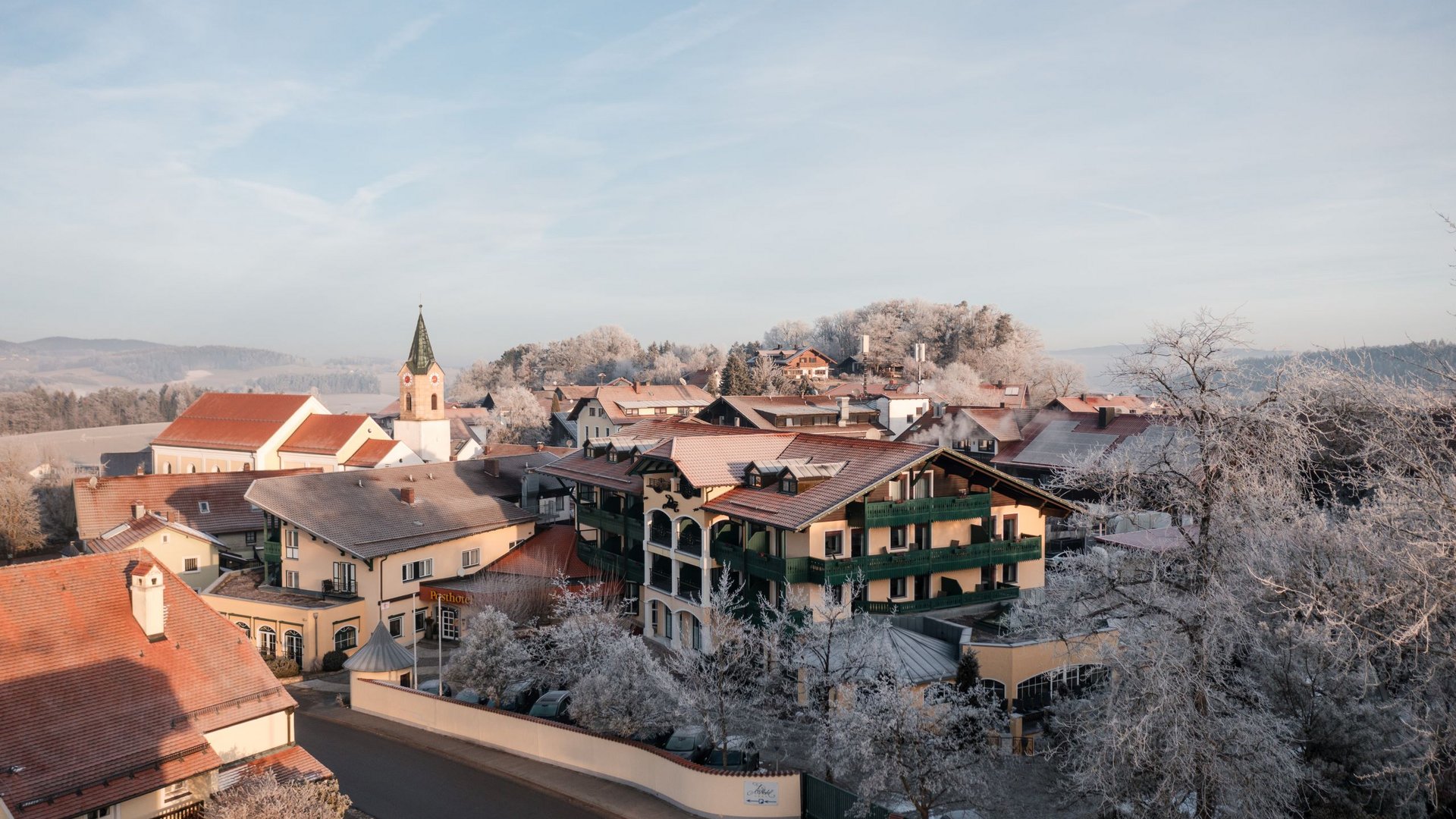 Winter village scene with houses and church tower under clear sky