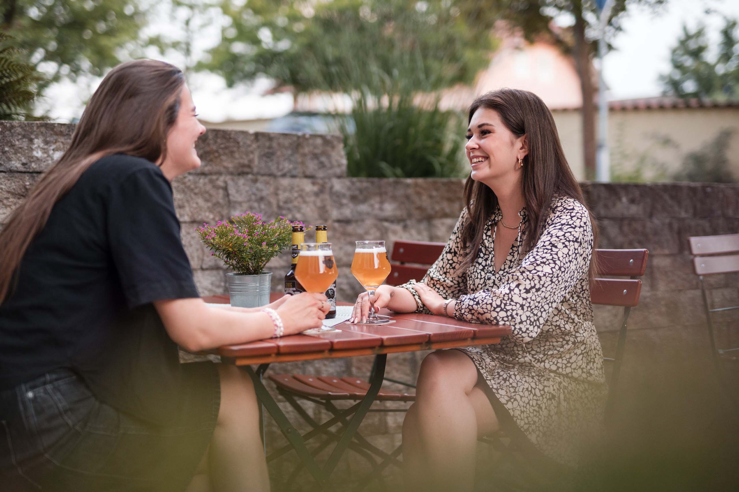 Two women sitting outdoors drinking beer and chatting